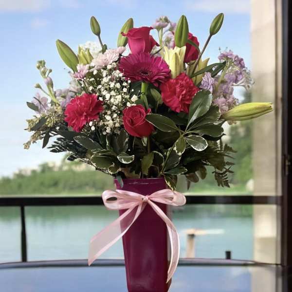 Pink and purple mixed bouquet in a magenta vase with a ribbon