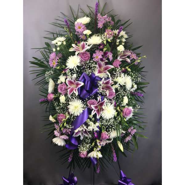 Standing floral spray with purple ribbon and pink, white, and lavender flowers