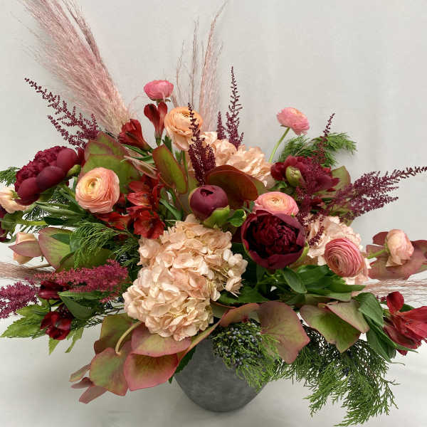 Mixed pink and burgundy floral arrangement in a gray vase