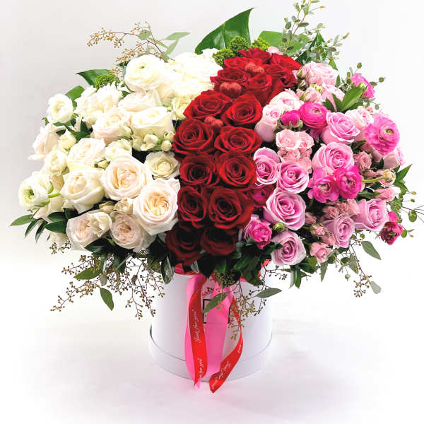 Large bouquet of red, white, and pink roses in a white hat box
