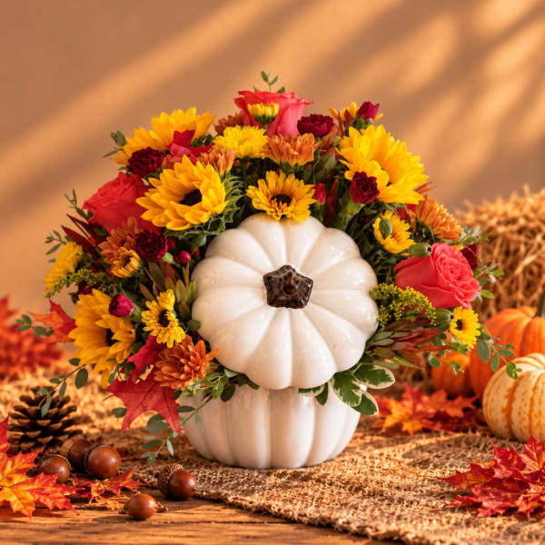 Fall floral arrangement in a white pumpkin vase with sunflowers and roses