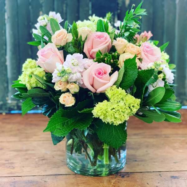 Pink and peach roses in a glass vase with green and white flowers