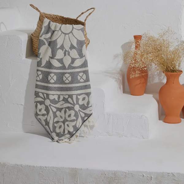Decorative wall display with woven basket, patterned textile, and terracotta vases