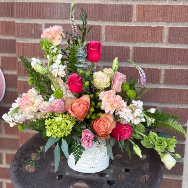 Mixed bouquet of pink, peach, and white flowers in a white vase