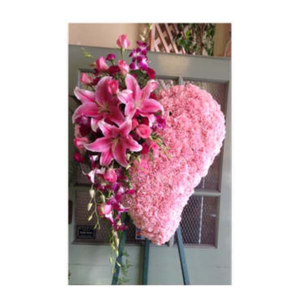 Heart-shaped pink floral standing spray with lilies and orchids