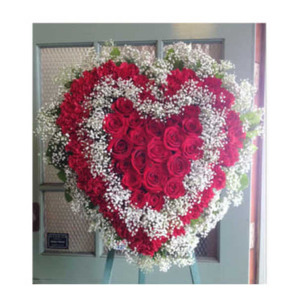 Heart-shaped standing spray of red roses with white baby's breath