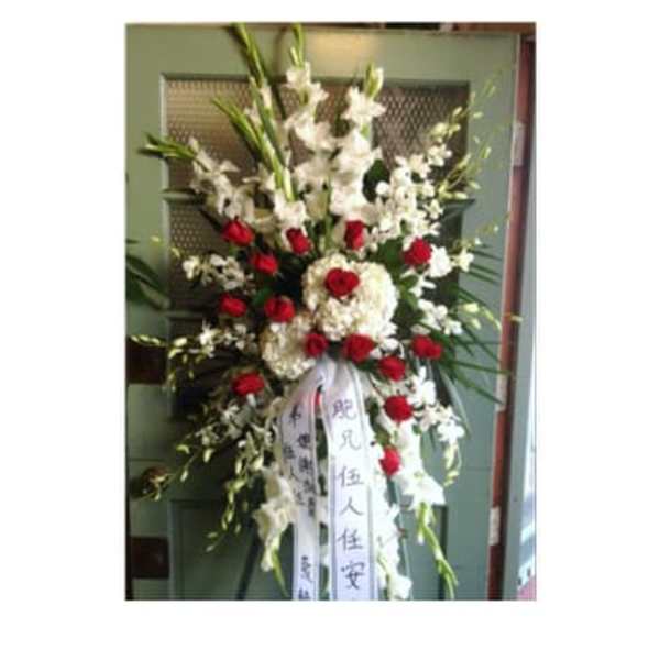 Tall standing floral spray with white flowers and red roses on a ribboned easel