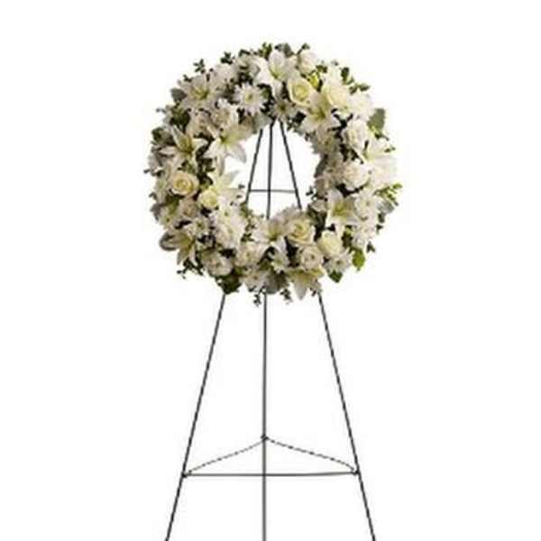 White floral funeral wreath on a metal easel