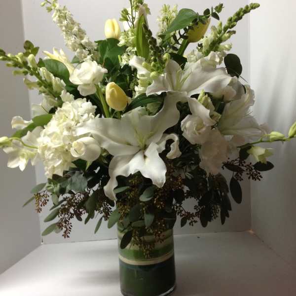 White lilies and tulips arranged in a glass vase