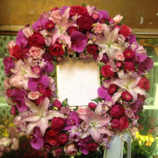 Heart-shaped floral wreath with pink and red flowers around a blank center