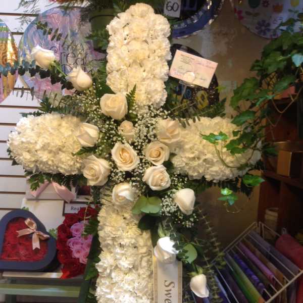 White floral cross with roses and a ribbon reading "Sweet Lani, Lovingly"