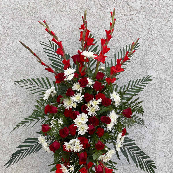 Standing floral spray with red roses and white daisies on a metal easel