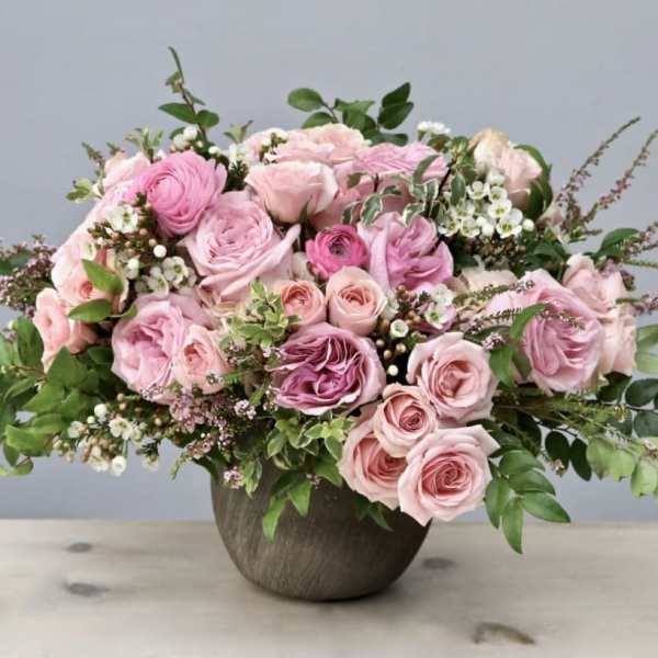 Pink roses arranged in a round vase with greenery