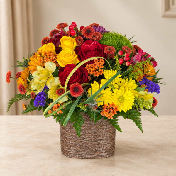 Colorful mixed bouquet in a woven basket with roses and daisies