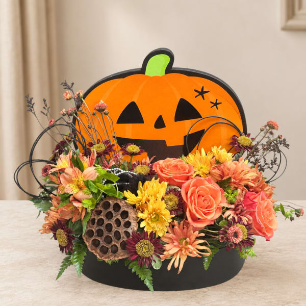 Halloween floral arrangement with roses and mums in a pumpkin display