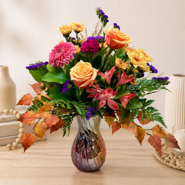 Mixed bouquet of roses, chrysanthemums, and alstroemeria in a glass vase