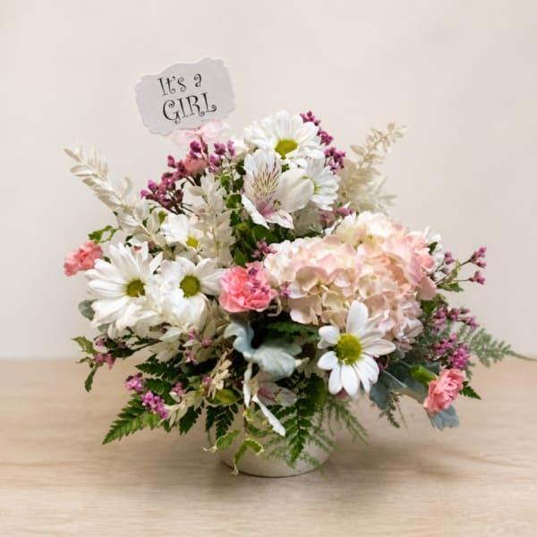 Pink and white flower arrangement in a vase with an "It's a GIRL" sign