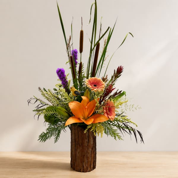 Tall tropical flower arrangement in a bark-covered vase with orange and purple blooms