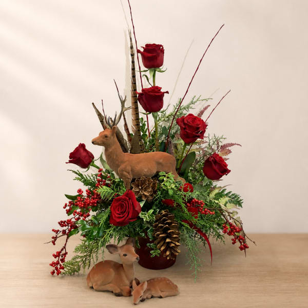 Red roses arranged with pinecones and deer figurines in a vase