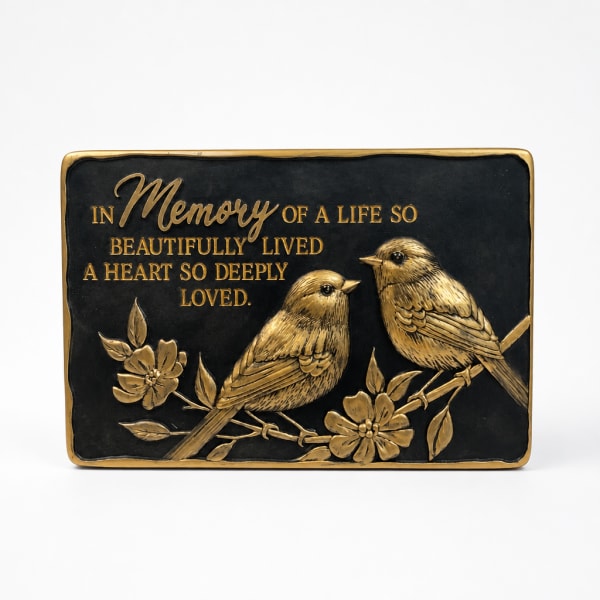 Black memorial plaque with gold birds and flowers