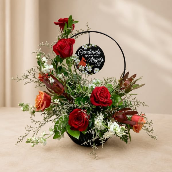 Red roses and white flowers in a black basket with a cardinal memorial sign