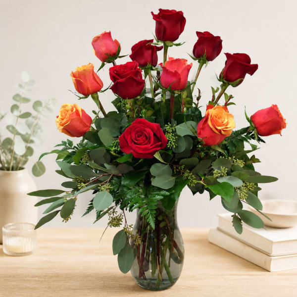 Red and orange roses arranged in a clear glass vase