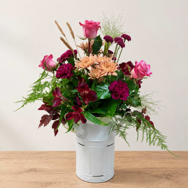 Mixed bouquet in a white metal bucket with pink and burgundy flowers