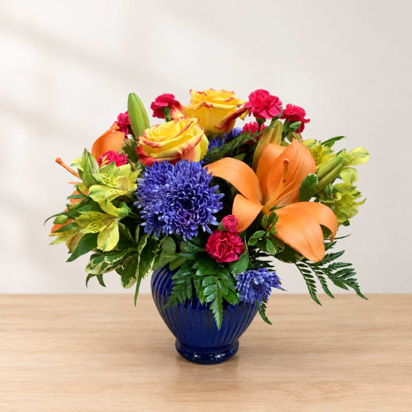 Colorful bouquet of roses, lilies, and chrysanthemums in a blue vase