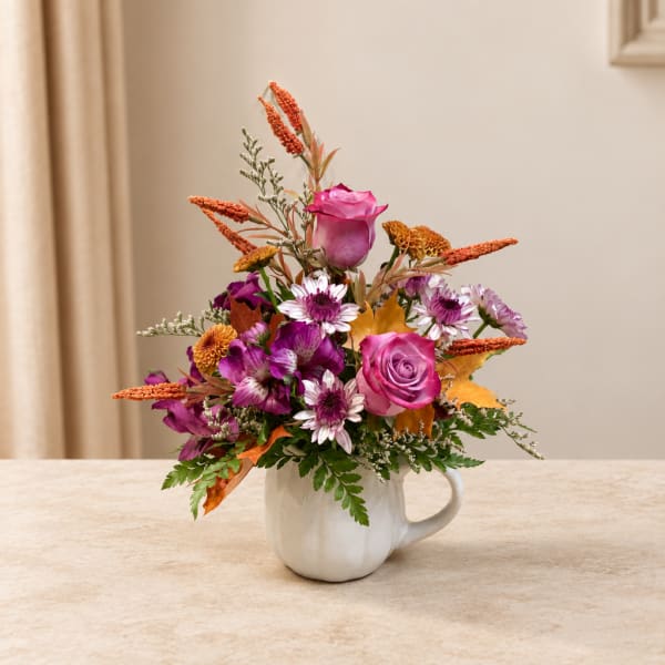 Pink and purple flower arrangement in a white mug vase