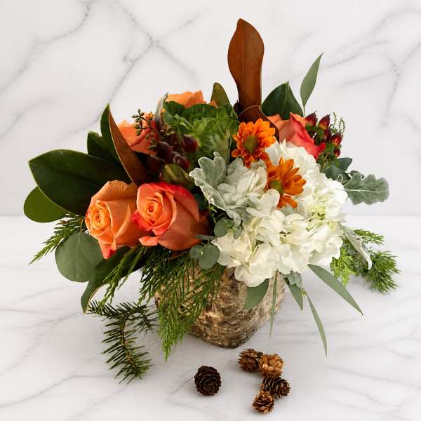 Orange roses and white chrysanthemums in a birch bark container with pinecones
