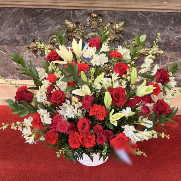 Large red and white floral arrangement in a white basket vase