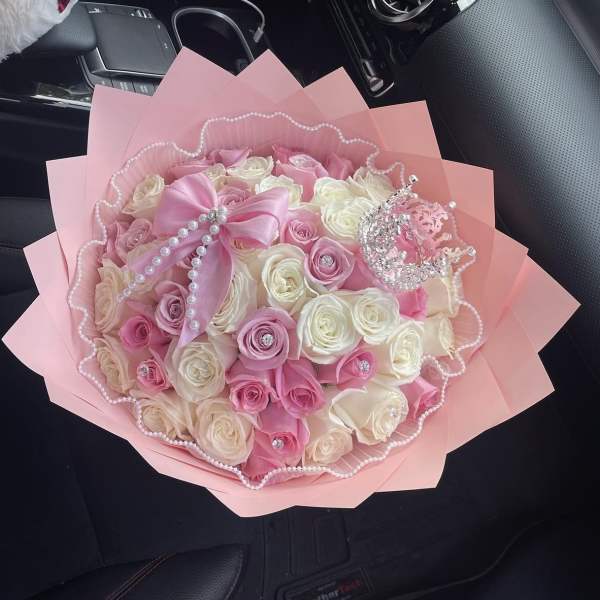 Pink and white rose bouquet wrapped in pink paper with pearl accents
