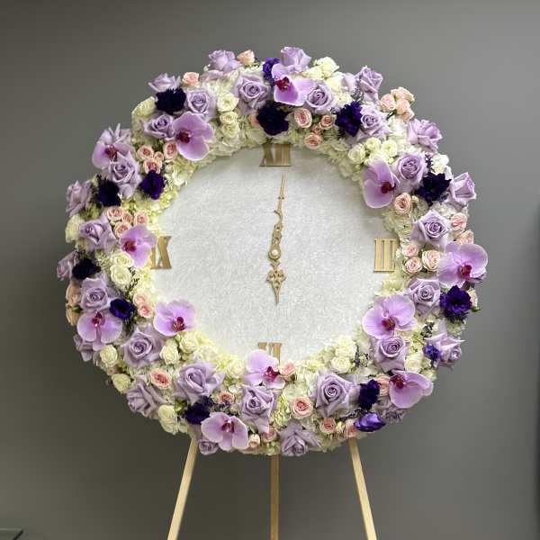 Large round floral wreath on an easel with lavender, white, and pink blooms