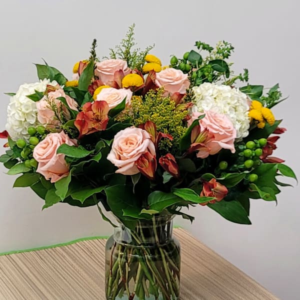 Pink roses and mixed flowers arranged in a glass vase