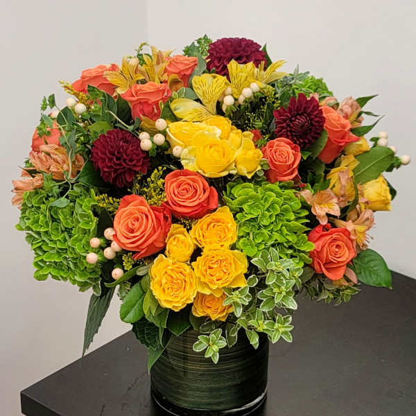 Colorful bouquet of roses, dahlias, and hydrangeas in a dark vase