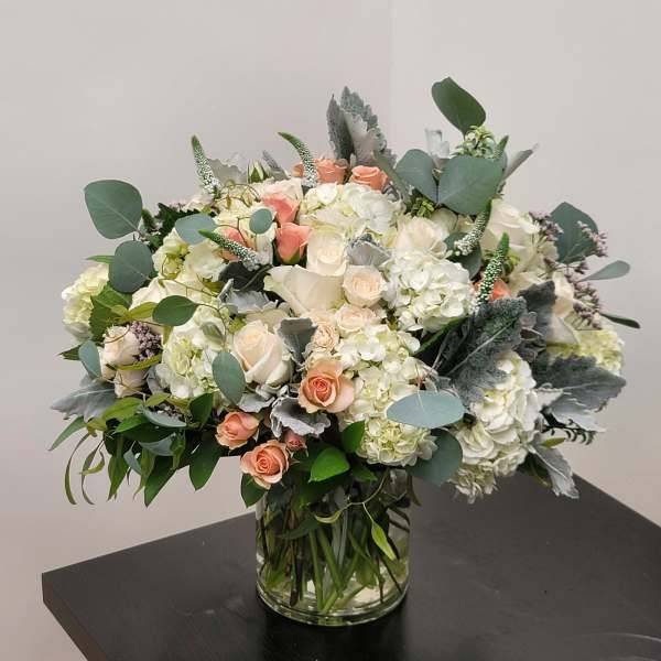 Bouquet of white hydrangeas and peach roses in a glass vase