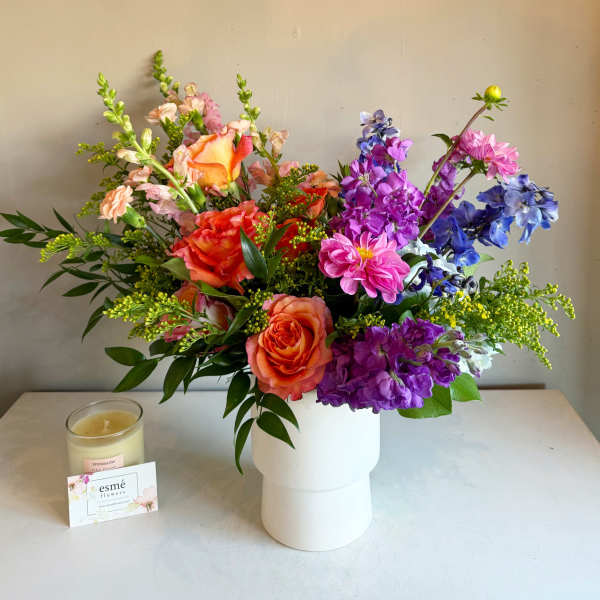 Colorful mixed bouquet in a white vase with pink, orange, purple, and blue flowers