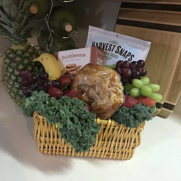 Fruit basket with pineapple, grapes, strawberries, and packaged snacks