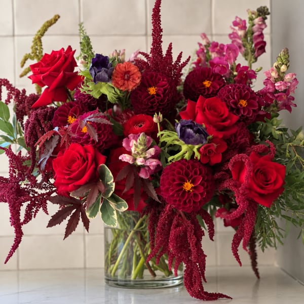 Red roses and burgundy dahlias in a clear glass vase