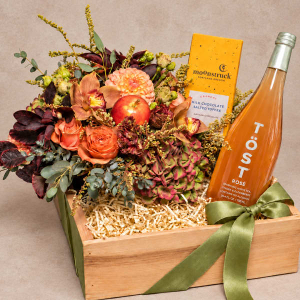 Flower gift box with orange blooms, chocolate, and a rosé bottle