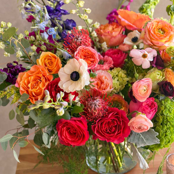 Mixed bouquet of orange, pink, red, and white flowers in a glass vase