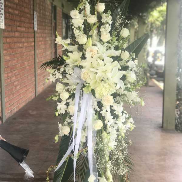 Tall white floral standing spray with lilies and roses on an easel