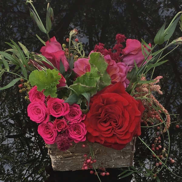 Pink and red roses arranged in a rustic wooden container