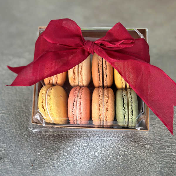 Box of colorful macarons tied with a red ribbon