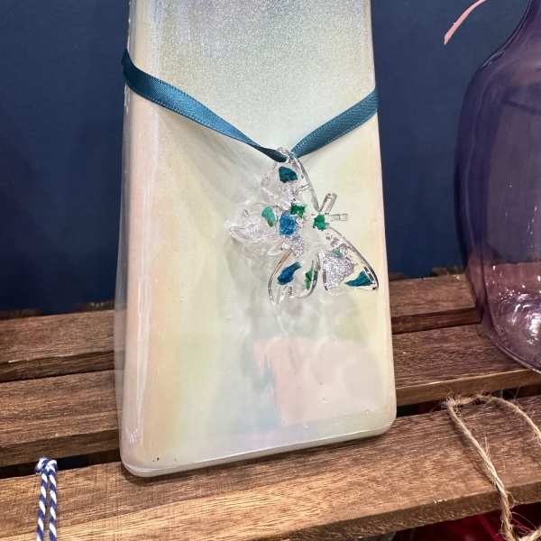 Decorative iridescent glass bottle with a blue ribbon and butterfly charm