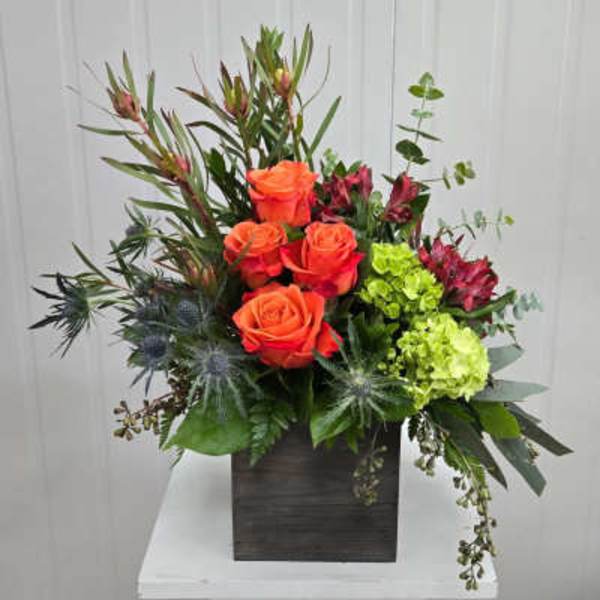 Orange roses and green hydrangeas in a dark square vase