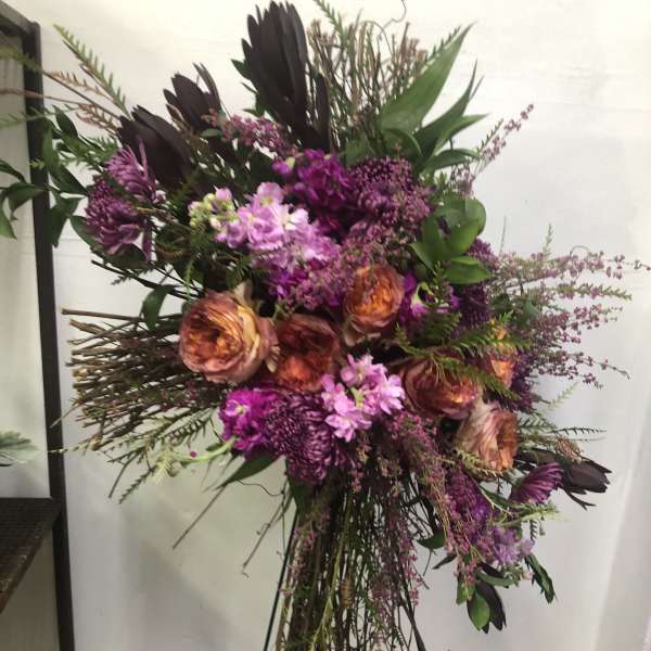 Tall floral spray with purple and peach blooms on a stand