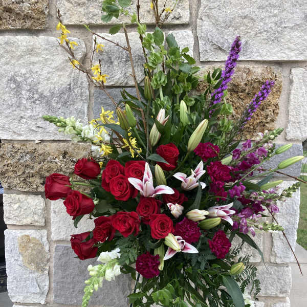Tall standing floral spray with red roses, lilies, and purple accents