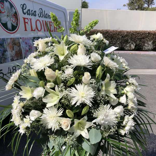 Large white funeral spray with lilies, roses, and spider mums