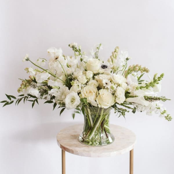 White floral arrangement in a clear glass vase on a small round table